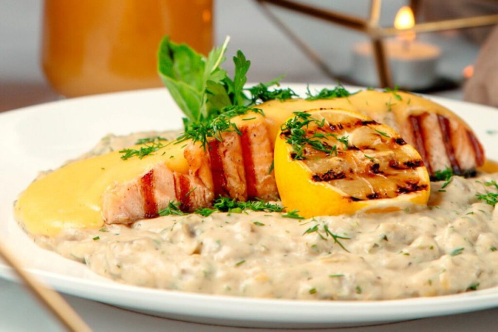 close up of grilled salmon and risotto garnished with lemon