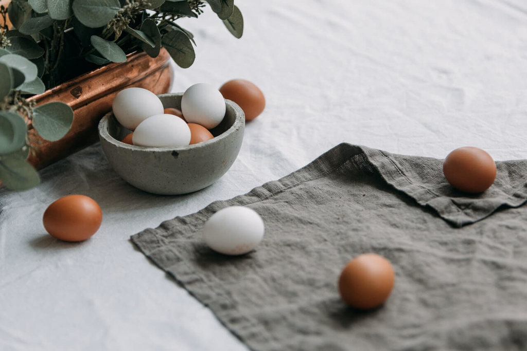 Cesta de ovos sobre um pano cinza simbolizando fonte de proteína animal
